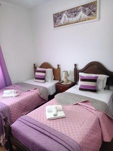 duas camas num quarto com lençóis roxos e brancos em Alojamento Local Largo da Igreja em Santiago do Cacém