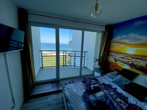 una camera da letto con una grande finestra con vista sull'oceano di Widok na Morze Porta Mare - Apartament 326 a Dziwnówek