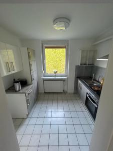cocina con suelo de baldosa blanca y ventana en Ferienhaus mit großem Garten en Oldenburg