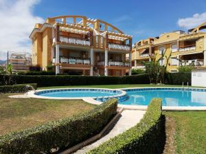 a villa with a swimming pool in front of a building at Bali Solo Familias Serviplaya in Playa de Xeraco