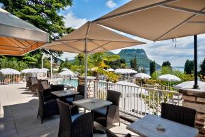 un patio con mesas, sillas y sombrillas en Hotel Excelsior Le Terrazze en Garda