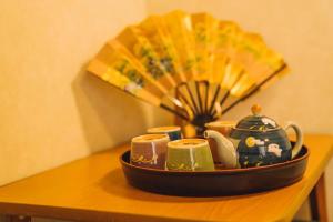 a tray with cups and a fan on a table at Kokoro no sato・RYUU in Kyoto