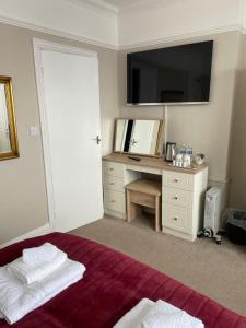 a bedroom with a bed with a desk and a television at The Sandrock in Clacton-on-Sea