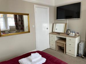 a bedroom with a bed and a desk with a mirror at The Sandrock in Clacton-on-Sea