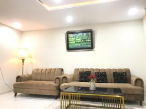 a living room with two couches and a tv on the wall at Mukhtar Homes Bahria Town Lahore in Lahore