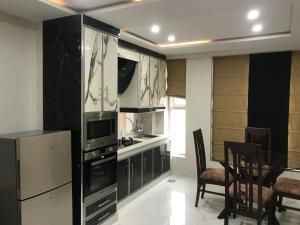 a kitchen with black cabinets and a table and chairs at Mukhtar Homes Bahria Town Lahore in Lahore
