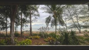 a view of a beach from a window with palm trees at SANTI beach retreat in Ban Rang Pla