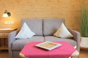 ein Wohnzimmer mit einem grauen Sofa und einem Tisch in der Unterkunft Leitnerhof in Bad Reichenhall