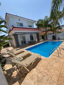 a swimming pool with two lounge chairs and a house at Villa Diana - 200 meters from Kapparis, Fireman's Beach in Paralimni