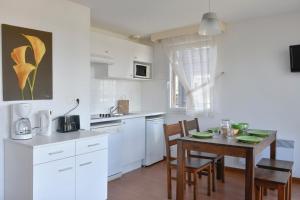 a kitchen with white cabinets and a table with chairs at Vacancéole - Domaine de Saint Orens in Montréal