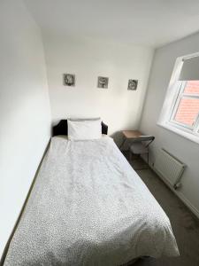 a bedroom with a bed with a white comforter and a window at Cheerful Heeley Home in Heeley