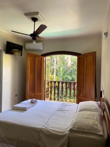 Pousada Dois Irmãos في ترينيداد: غرفة نوم مع سرير ونافذة مع شرفة