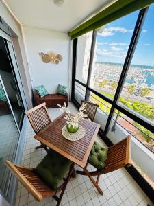 - une salle à manger avec une table, des chaises et des fenêtres dans l'établissement Studio chic et cosy vue mer, à La Grande Motte