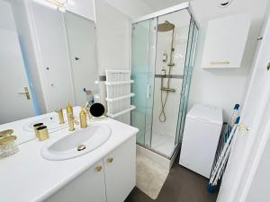 a white bathroom with a sink and a shower at Studio chic et cosy vue mer in La Grande-Motte