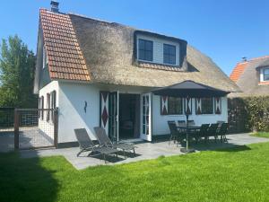 ein Haus mit einer Terrasse mit Stühlen und einem Sonnenschirm in der Unterkunft Villa Stilleven in Callantsoog