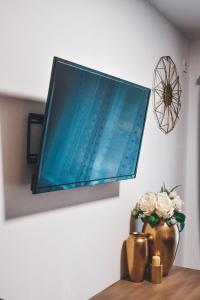 a television hanging on a wall with a vase with flowers at Villa-Apartments Bognar in Velika