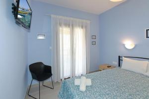 een blauwe slaapkamer met een bed en een zwarte stoel bij Agapitos Apartments in Nikiti