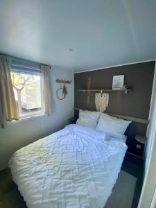a bedroom with a white bed and a window at Ruhig gelegenes Mobilhome La Carabasse in Vias
