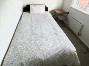 uma cama com um edredão branco num quarto em Cheerful Heeley Home em Heeley