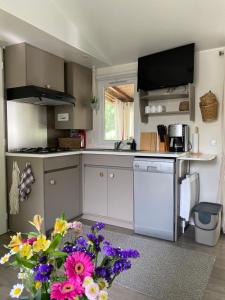 a kitchen with white cabinets and flowers in the foreground at Ruhig gelegenes Mobilhome La Carabasse in Vias