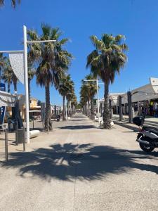une rue avec des palmiers et une moto garée dans la rue dans l'établissement Ruhig gelegenes Mobilhome La Carabasse, à Vias
