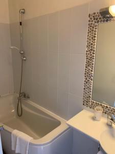 W łazience znajduje się wanna, umywalka i lustro. w obiekcie Hôtel Colombo- Porto Corse w mieście Porto Ota
