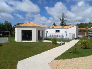 una pequeña casa blanca con un patio de césped en Au Logis des Mûriers en Vairé