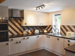 a kitchen with white cabinets and black counter tops at Beudy Bach-oh5 in Dihewid