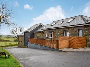 a stone house with a deck on a driveway at Beudy Bach-oh5 in Dihewid