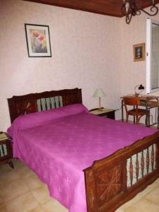 a bedroom with a wooden bed with a purple blanket at Gîte Saint Michel 2 étoiles in Moulin-Mage