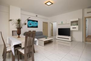 uma sala de estar com um sofá, uma mesa e uma televisão em Apartments Lea em Podstrana