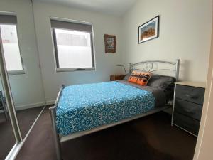 um quarto com uma cama com um edredão azul e uma janela em Beach Life em Aspendale