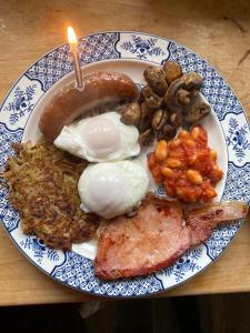 a blue and white plate of food with eggs meat and mushrooms at Greenhill Farm Barn B&B in Sutton under Brailes