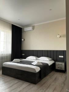 1 dormitorio con 1 cama grande y cabecero negro en JETISY COMPLEX, en Taraz