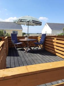a table and chairs on a deck with an umbrella at The Getaway, Miltown Malbay in Miltown Malbay