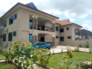 una casa con un coche azul delante de ella en Stunning Executive 2 Bedroom Apartment with KING SIZE BED en Kumasi