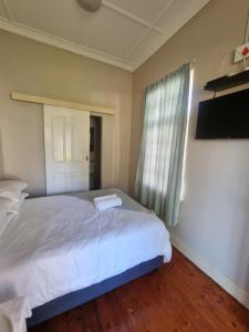 ein Schlafzimmer mit einem großen weißen Bett und einem Fenster in der Unterkunft Capital On French Guest House in Pietermaritzburg