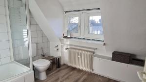 a white bathroom with a toilet and a window at Ferienwohnung Ollywood Hill in Halbs +17 photos