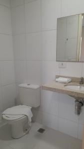 a white bathroom with a toilet and a sink at Anhembi Hostel in Sao Paulo