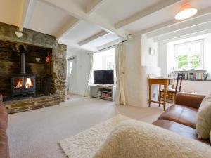 uma sala de estar com lareira e sofá em Ayr Cottage em Tintagel