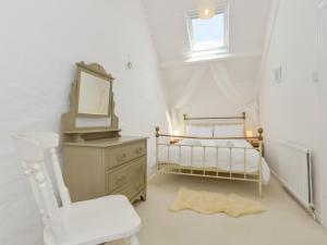 um quarto com uma cama, um espelho e uma cadeira em Ayr Cottage em Tintagel