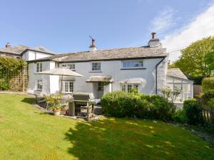 uma casa branca com um guarda-chuva e um quintal em Ayr Cottage em Tintagel