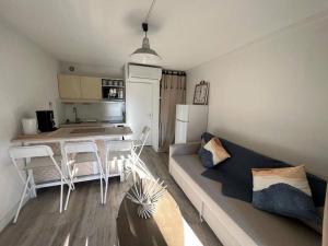 a living room with a couch and a table and a kitchen at Les Tropéziennes in Cogolin