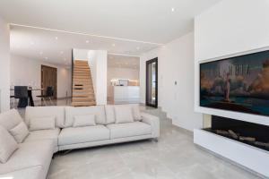 a living room with a white couch and a flat screen tv at Sea views in Cap de Creus - Free WIFI - LUMEN HOUSE in Port de la Selva