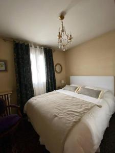 um quarto com uma grande cama branca e um lustre em Les Marmottes em Arpajon-sur-Cère