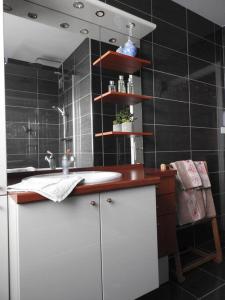 a bathroom with a white sink and black tiles at Les Marmottes in Arpajon-sur-Cère