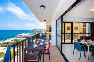 a balcony with a table and chairs and the ocean at Islet Promenade Seafront Apartment with large Corner Terrace by Getawaysmalta in St Paul's Bay