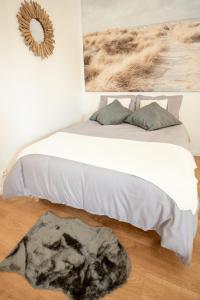 - une chambre avec un lit doté de draps blancs et d'un tapis dans l'établissement LES DUNES Studio Cosy-Terrasse-Parking -Proche paris, à Vitry-sur-Seine