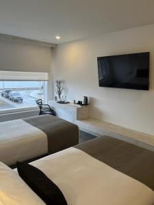 Habitación de hotel con 2 camas y TV de pantalla plana. en Hotel Costanera, en Puerto Natales