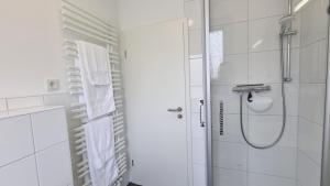 a white bathroom with a shower and a glass door at Haus Polarstern Ferienwohnung Kapella in Borkum +30 photos